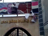 Syria protestor removes poster of Hafez al-Assad