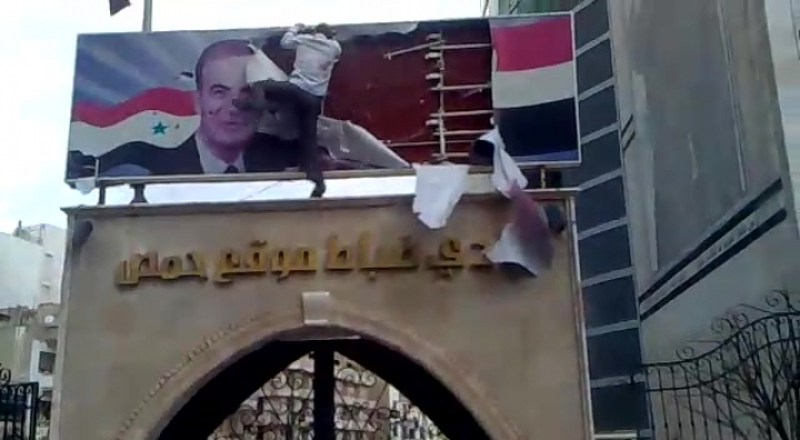 Syria protestor removes poster of Hafez al-Assad